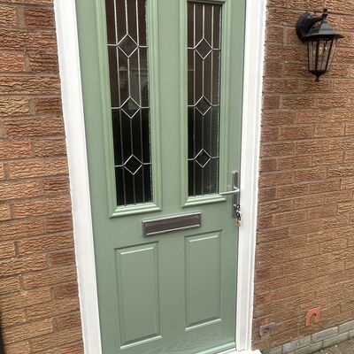 Newly fitted sage green composite front door with decorative glass panels and silver handle.