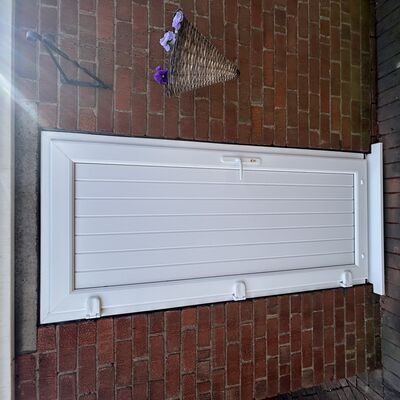 Newly fitted white uPVC side door with vertical panels and white handle.