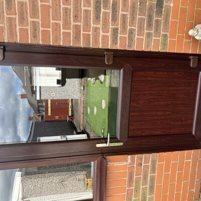 Newly fitted rosewood uPVC back door with glass panel and silver handle.